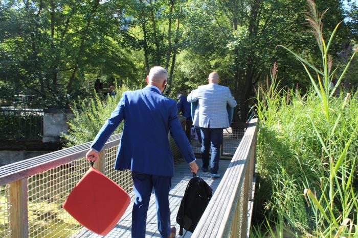 Mitarbeiter tragen ein rotes Sitzm&ouml;bel &uuml;ber einen Steg im Zoo Dresden