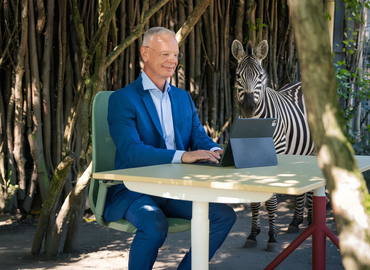Mann arbeitet am Laptop an einem Tisch vor der Zebra-Anlage